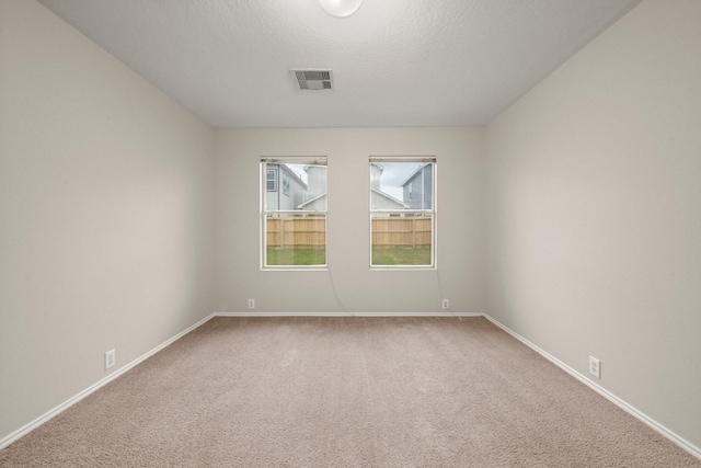 empty room featuring carpet, a textured ceiling, visible vents, and baseboards