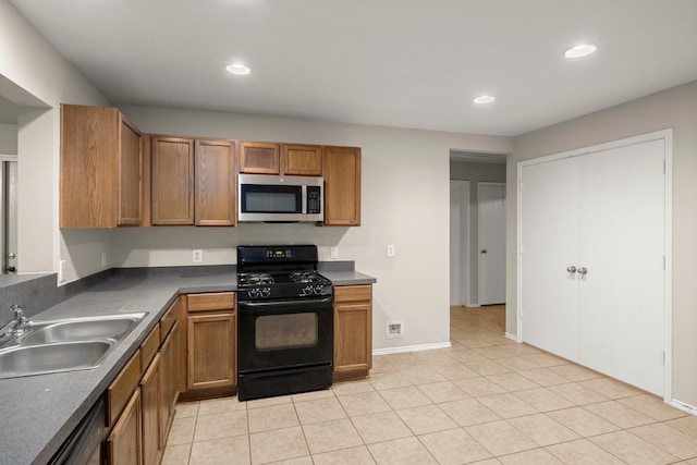 kitchen with light tile patterned flooring, a sink, black appliances, brown cabinetry, and dark countertops