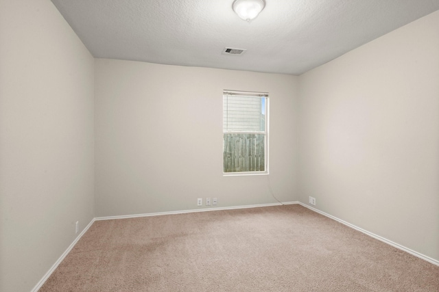 unfurnished room with a textured ceiling, carpet, visible vents, and baseboards