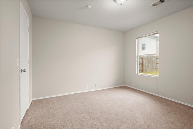 carpeted spare room with visible vents, a textured ceiling, and baseboards