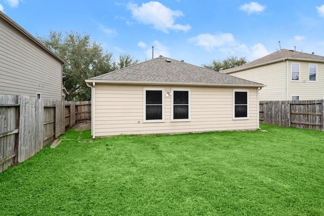 back of house featuring a fenced backyard, a shingled roof, and a lawn