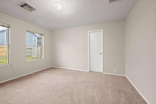 carpeted spare room featuring baseboards, visible vents, and a textured ceiling