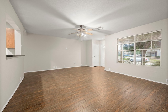 unfurnished room with baseboards, visible vents, ceiling fan, dark wood-type flooring, and a textured ceiling