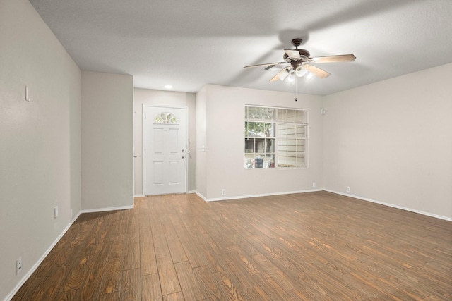 spare room featuring ceiling fan, baseboards, and wood finished floors