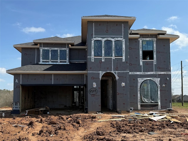 property in mid-construction with an attached garage and roof with shingles