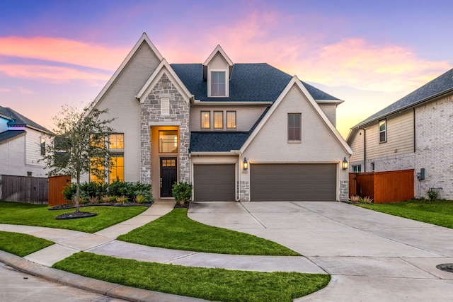 view of front of house featuring concrete driveway, stone siding, an attached garage, fence, and a yard