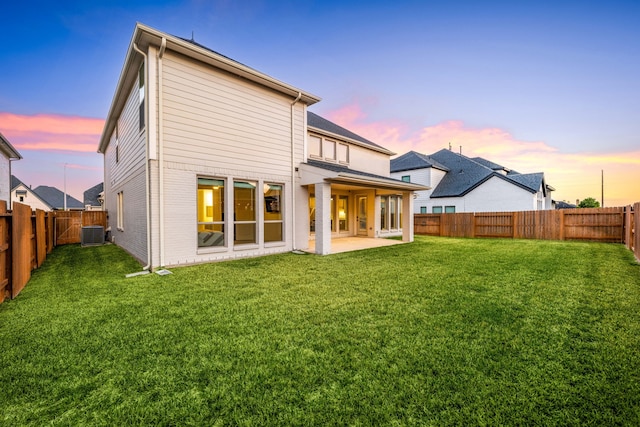 back of property at dusk with a patio area, a fenced backyard, a lawn, and central AC unit