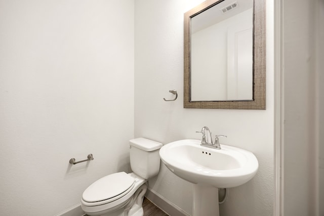 bathroom with toilet, baseboards, visible vents, and a sink