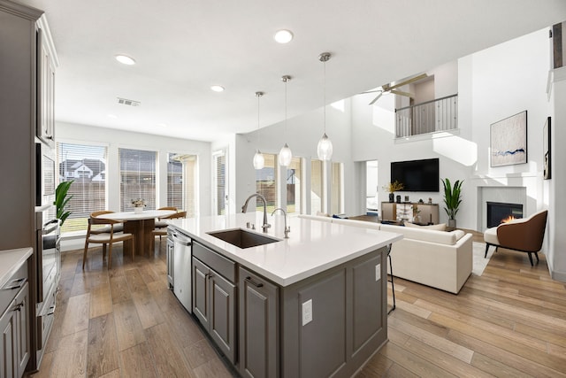 kitchen with visible vents, wood-type flooring, appliances with stainless steel finishes, a lit fireplace, and a sink