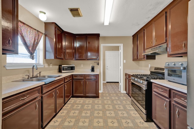 kitchen with under cabinet range hood, stainless steel appliances, a sink, visible vents, and light floors