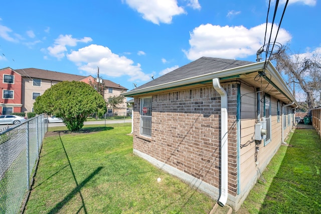 view of home's exterior featuring a yard, brick siding, and fence