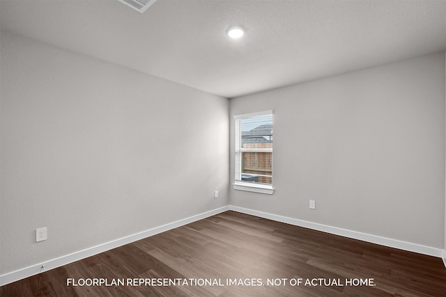 empty room with visible vents, dark wood finished floors, and baseboards