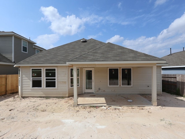 rear view of house with a patio area, roof with shingles, and a fenced backyard