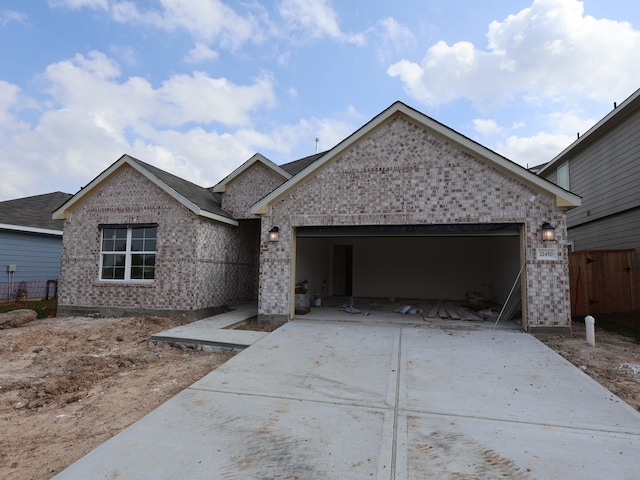 single story home with concrete driveway, brick siding, an attached garage, and fence