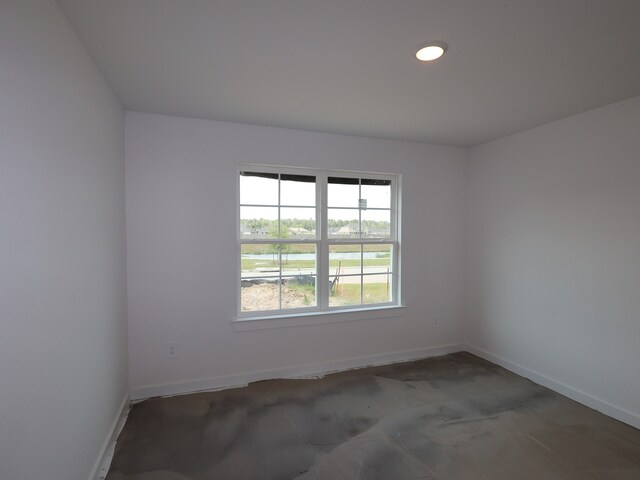 unfurnished room featuring concrete flooring and baseboards