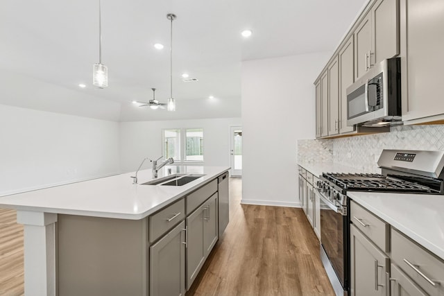 22450 Birchfield Grove Ln, New Caney, TX 77357 - kitchen featuring stainless steel appliances, gray cabinets, light wood finished floors, tasteful backsplash, and light countertops
