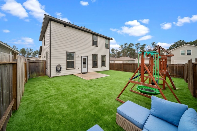 rear view of house with a patio, a lawn, a playground, and a fenced backyard