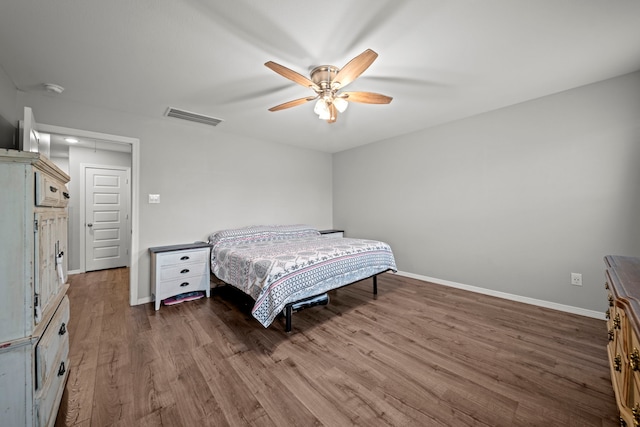 bedroom with ceiling fan, wood finished floors, visible vents, and baseboards