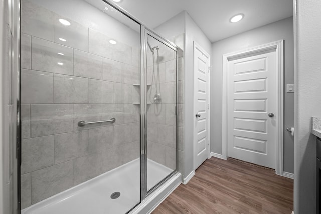 bathroom featuring a stall shower, baseboards, wood finished floors, vanity, and recessed lighting