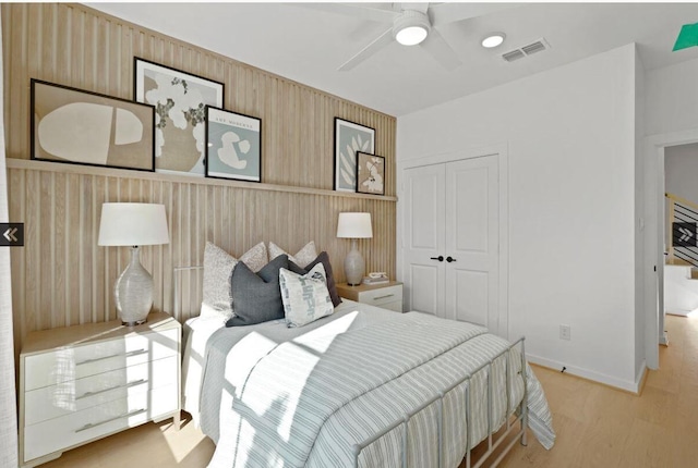 bedroom with a closet, visible vents, a ceiling fan, wood finished floors, and baseboards