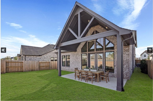 back of property with brick siding, a lawn, a patio area, and a fenced backyard