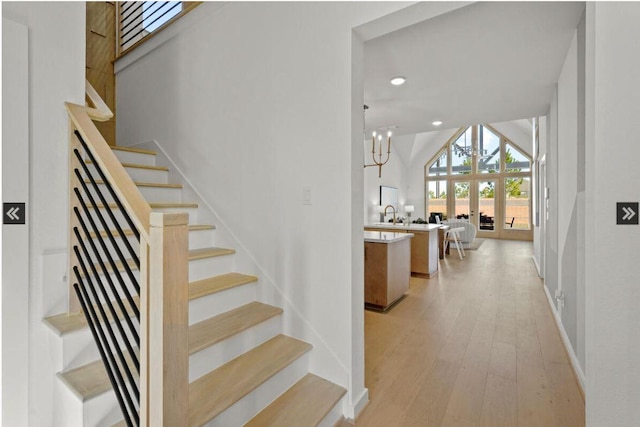 stairway with french doors, a notable chandelier, recessed lighting, vaulted ceiling, and wood finished floors