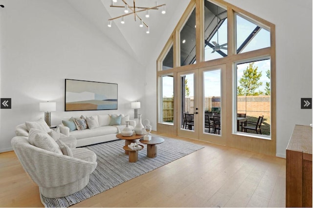 living room with wood finished floors, french doors, high vaulted ceiling, and a notable chandelier