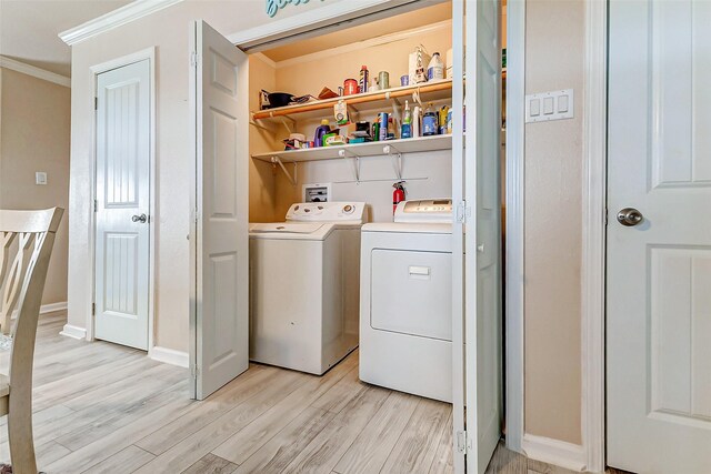 washroom featuring laundry area, baseboards, washer and clothes dryer, ornamental molding, and light wood-style floors