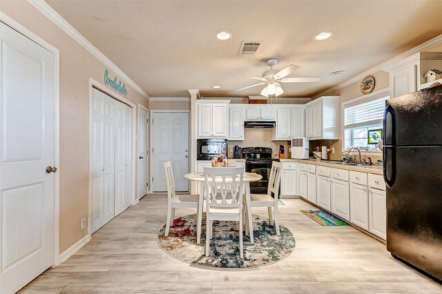 kitchen with crown molding, visible vents, white cabinets, a sink, and black appliances