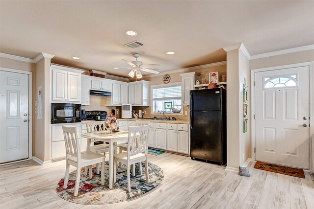 kitchen with visible vents, white cabinets, light wood-style flooring, under cabinet range hood, and black appliances