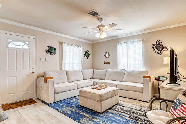 living area featuring plenty of natural light, light wood-type flooring, visible vents, and crown molding