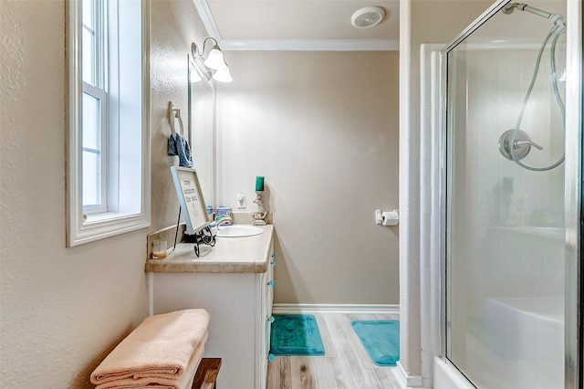 full bath with crown molding, a shower stall, vanity, wood finished floors, and baseboards