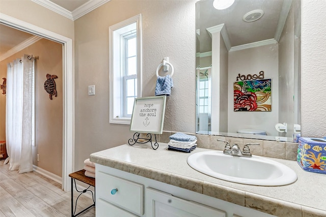 bathroom featuring crown molding, a textured wall, toilet, vanity, and wood finished floors