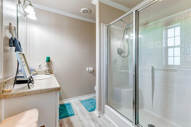 bathroom with wood finished floors, vanity, baseboards, ornamental molding, and a stall shower