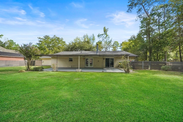 rear view of house with a yard, french doors, a patio area, and a fenced backyard