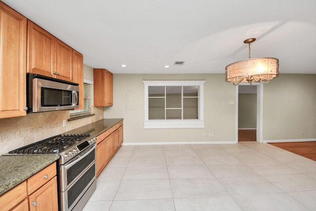 kitchen featuring tasteful backsplash, baseboards, visible vents, dark stone countertops, and stainless steel appliances