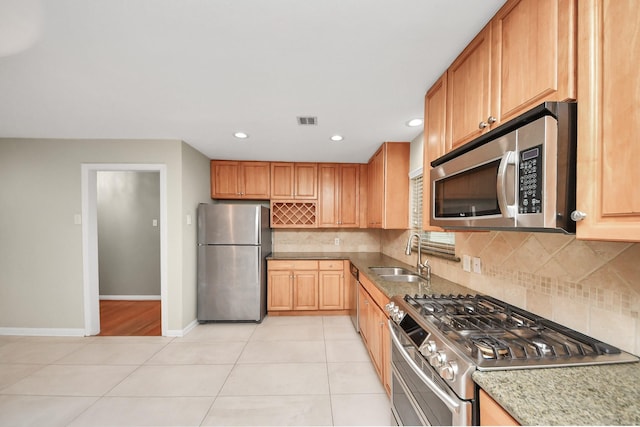 kitchen with light tile patterned flooring, a sink, visible vents, appliances with stainless steel finishes, and backsplash