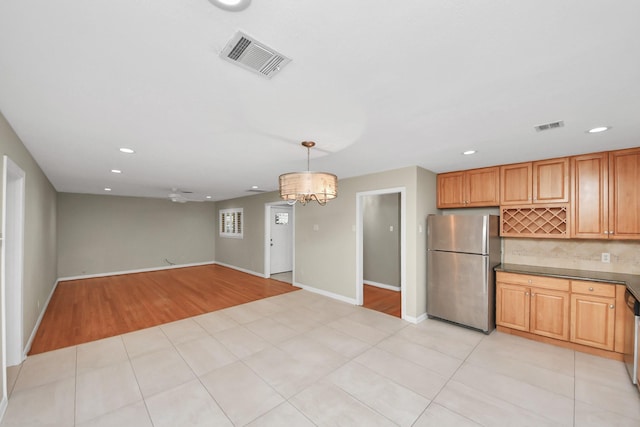 kitchen with dark countertops, light tile patterned floors, visible vents, and freestanding refrigerator