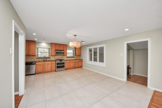 kitchen featuring baseboards, stainless steel appliances, a sink, and decorative backsplash