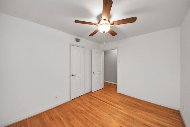 empty room with light wood finished floors, baseboards, visible vents, and ceiling fan