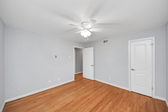 empty room with light wood-style flooring, visible vents, baseboards, and a ceiling fan