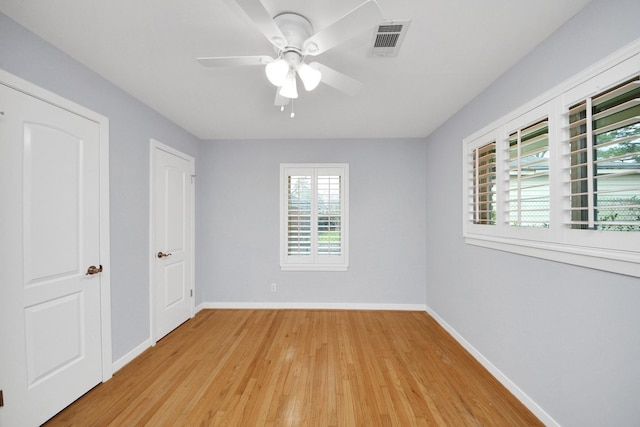 unfurnished room featuring light wood-style floors, a ceiling fan, visible vents, and baseboards