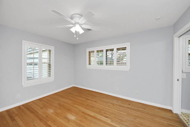 spare room featuring baseboards, a ceiling fan, light wood-style flooring, and a healthy amount of sunlight