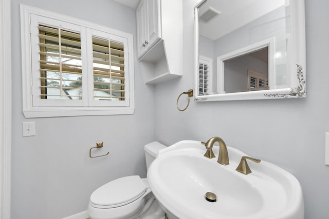 bathroom with toilet, a sink, and visible vents