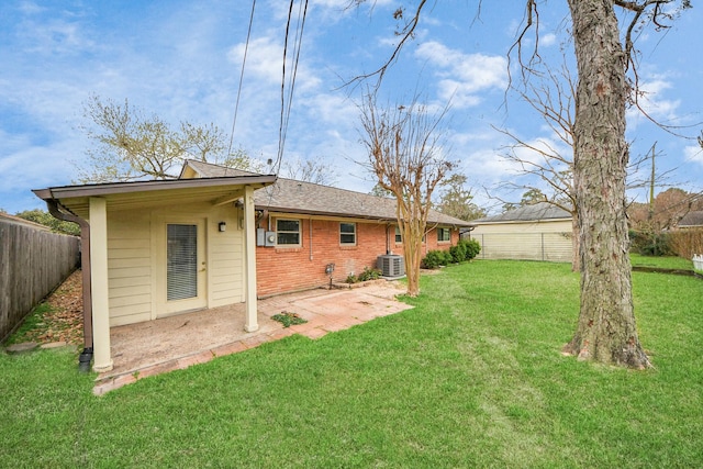 rear view of property featuring brick siding, a patio, a yard, central air condition unit, and a fenced backyard