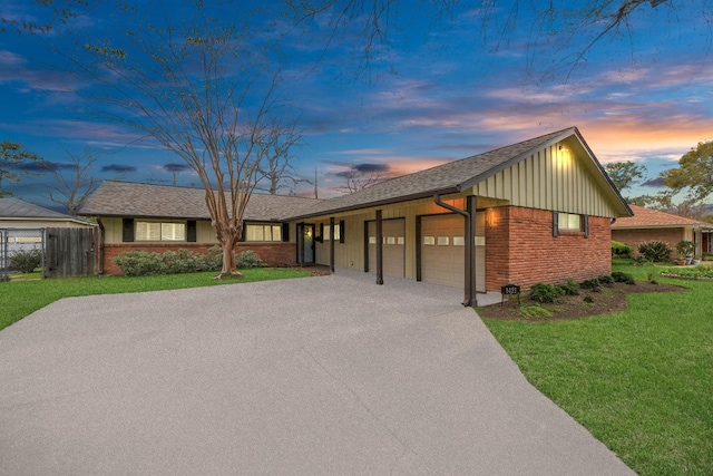 view of front facade featuring an attached garage, a front yard, aphalt driveway, and brick siding