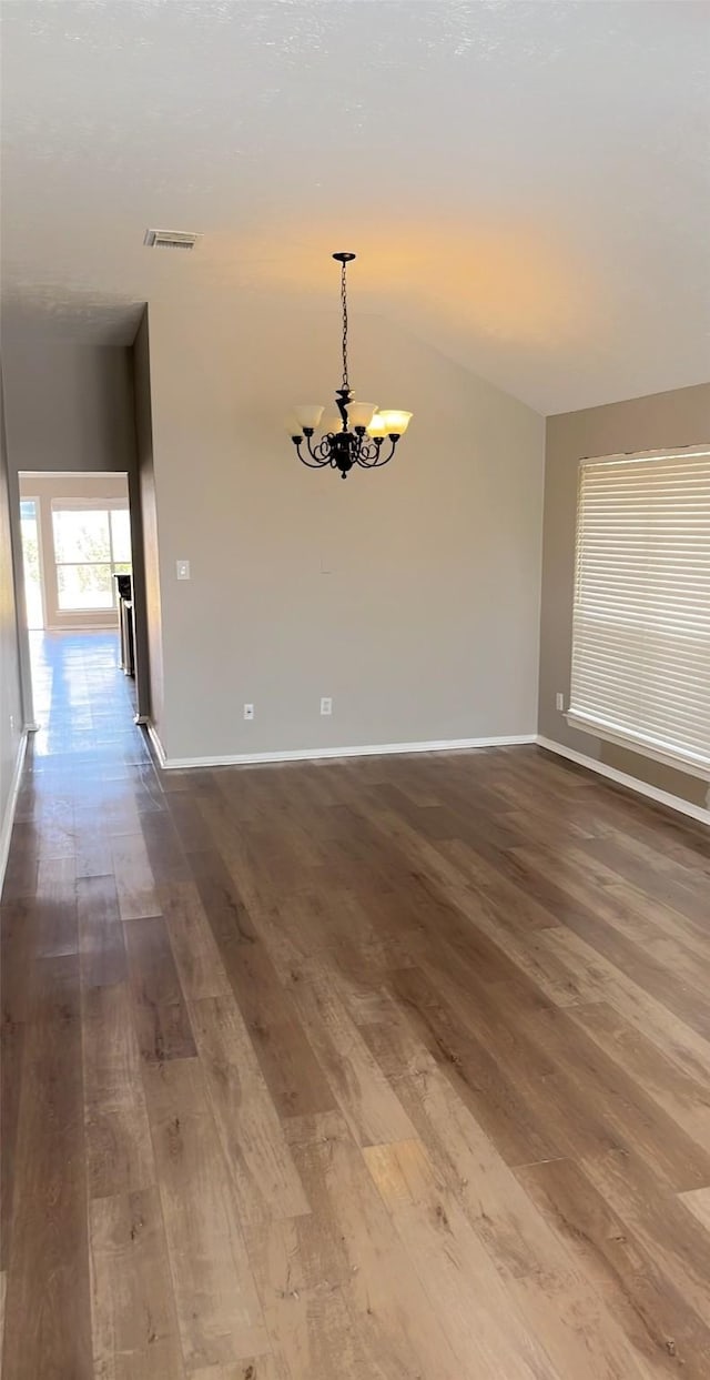 empty room with a chandelier, visible vents, baseboards, and dark wood-style floors