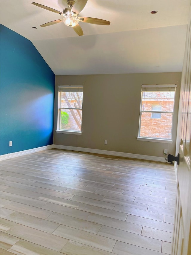 spare room with a ceiling fan, vaulted ceiling, baseboards, and wood finished floors