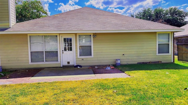 rear view of property with a yard, a shingled roof, a patio area, and fence