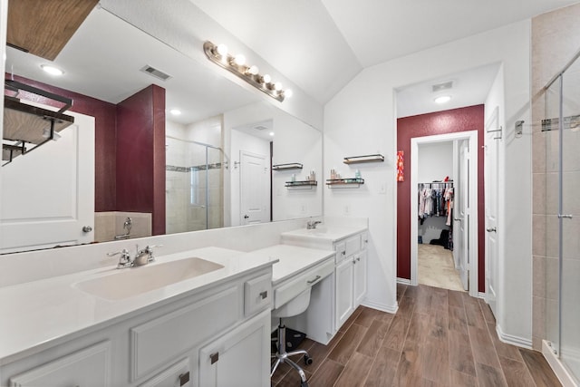 bathroom with wood finished floors, a sink, visible vents, double vanity, and a stall shower